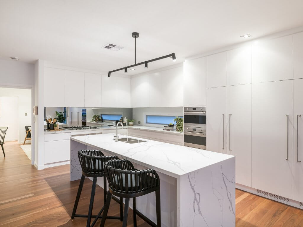 Modern white kitchen with marble benchtops after renovations